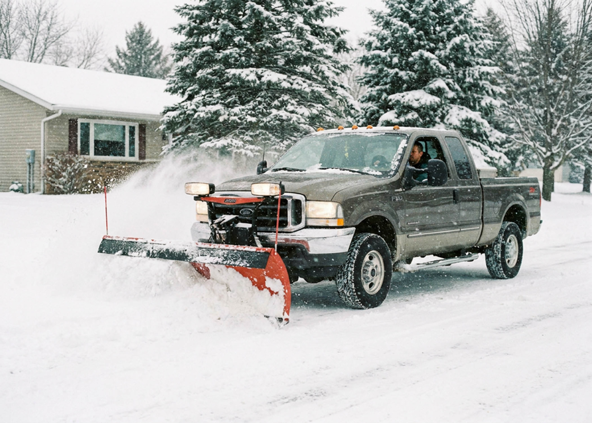 Pickup truck with snow plow clearing a residential driveway in Central Massachusetts